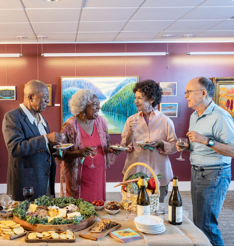 Group of seniors enjoying food and drinks at art gallery reception